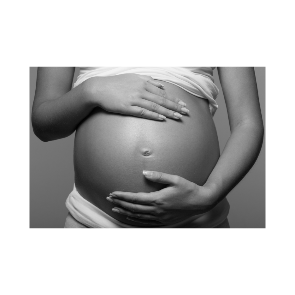 Black and white photo of a pregnant belly with hands on a plain background